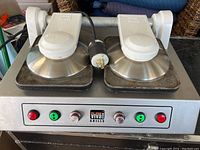 Full frontal view of the stainless steel Viva Grill with two round upper plates with lifting handles, control panel with indicator lights, and commercial power plug.