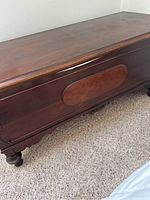 Front and side view of antique cedar chest showing wood finish, front panel design, and condition.