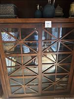 Front view of bookcase showing lattice-pattern glass doors and open top shelf