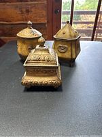 Three antique-style decorative canisters with intricate embossed detailing on black surface.