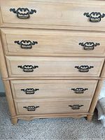 Front view of light wood dresser with five drawers and metal handles