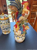Overall shot showing large rooster figurine, medium rooster lid canister, pasta jar with lid