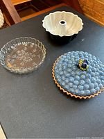 Clear glass pie dish with floral pattern, ceramic bundt pan with black exterior and white interior.
