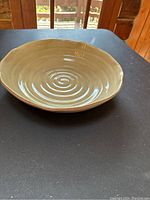 Top view of large cream-colored ceramic bowl showing circular spiral pattern and glossy finish