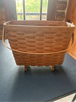 Full view of the rectangular woven wooden magazine holder basket with handle, showing the general structure and condition.