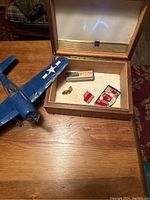 Handcrafted blue military plane, Marine harmonica, patches, buttons, and wooden box on table