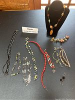 Full view of all jewelry laid flat and necklace on black display stand showing 6 necklaces, 4 bracelets, 1 pair earrings.