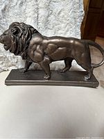 Side view of the bronze walking lion statue on rectangular base