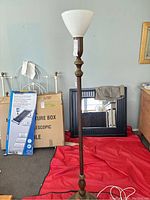 Full view of the antique floor lamp showing entire height, wooden base, and glass shade with background items.