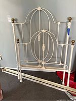 Full view of the iron bedframe with headboard, footboard, and rails visible showing overall structure and design.