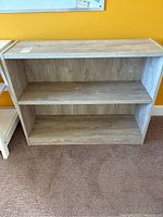 Front view of bookshelves showing two shelves and three compartments with natural light wood finish.