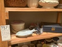 Photo of shelf containing various small decorative containers and a white fish-shaped dish with jewelry near the boxed jewelry storage.
