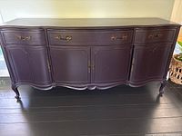 Front view of the dining buffet showing three drawers and four cupboard doors with brass handles and curved details
