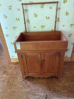 Front view of wooden dry sink with towel rack and two doors below.