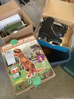 Photo showing the unopened box for large inflatable T-Rex costume and a box with black ice skates inside.