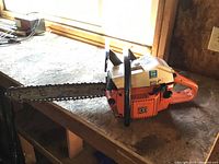 Side view of Husqvarna Model 44 chainsaw showing entire chainsaw on wooden surface.
