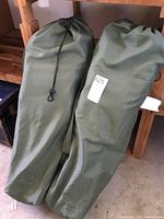 Two green fabric carrying bags with drawstrings lying on floor.