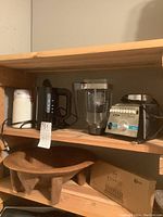 Shelf with Bodum electric kettle, Osterizer blender, and wooden bowl stand with boxed bamboo drying rack underneath