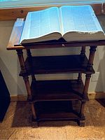 Full view of the wood lectern with Webster's dictionary open on top, showing the lectern's structure and book pages.