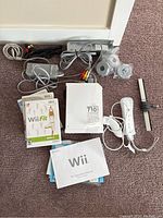 Full lot showing Wii console, controllers, sensor bar, cables, manuals, and game cases.