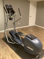 Full view of Precor elliptical on black exercise mat in finished room