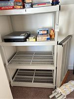 Full view of shelving unit with miscellaneous items on top shelf and some shelves empty.