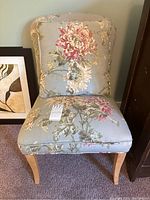 Front view of side chair showing seat and backrest with large floral print on light blue fabric