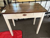 Full front view of white painted side table showing drawer with metal handle and dark wooden top with visible grain.