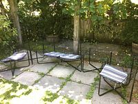 Wide view of loveseat, chairs, and tables arranged on patio with cushions in blue and white stripes.