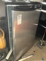 Photo of the stainless steel front panel with black handle of the bar fridge showing overall exterior condition.