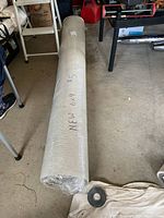 Photo of the full rolled carpet wrapped in protective plastic with dimensions and condition marked on the wrap.