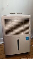 Front view of white ForestAir dehumidifier with air vent grill and water level indicator window.