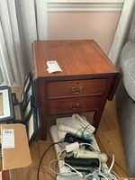 Front view of the wooden drop leaf table showing two drawers and brass handles.
