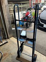 Full angled view of the large blue metal moving cart showing the frame, handles, and base plate with rust visible.