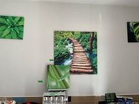Four stretched canvas prints on wall: large wooden bridge print and three smaller green plant leaf prints