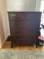 Front view of vintage wood secretary desk with five drawers and wooden knobs, positioned against wall.