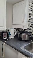 Photo showing all three small appliances on kitchen counter: crockpot, kettle, and toaster.