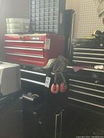 Front view of black Mastercraft Maximum tool chest with five drawers, ear defenders hanging on side and pegboard behind.