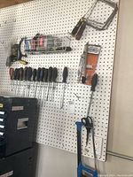 Photo of pegboard with multiple screwdrivers, coping saws, and a bow saw mounted.
