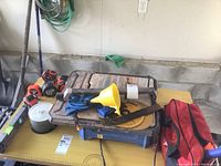 Photo of folding work bench with several tape measures, repair kit items, funnel, and spool of discs.