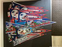 Top view of multiple New England Patriots blue, red, and white felt pennants stacked together showing logos and Super Bowl champion years.