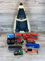 Photo shows a white and blue GI Joe space shuttle vehicle, multiple vintage View-Master viewers in red and blue, and several small vintage toy trains and vehicles in various colors laid out on wood flooring.