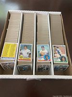 Four rows of loose 1983 Topps baseball cards in storage box, front row shows checklist card
