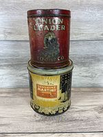 Front view of two stacked antique tins: red Union Leader Tobacco tin on top and yellow Sunshine Martini Cracker tin on bottom, showing wear