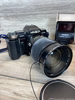 Minolta Maxxum 7000 camera body with attached zoom lens showing front and side details including lens markings and camera model.