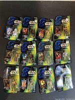 Full lot of 12 Star Wars action figures sealed in original blister packages arranged for display. Packaging features Star Wars branding with Darth Vader image, includes store price stickers.