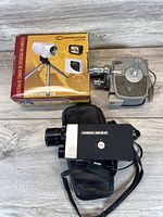 Overview photo showing boxed Centurion video camera with tripod, vintage grey film camera, black Super 8mm camera with case.