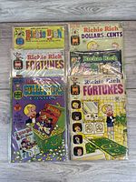 Seven vintage Richie Rich comic books laid out on floor, showcasing various titles and colorful covers.