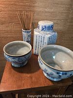 Photo showing all four pieces including the ginger jar, two bowls, and the vase with incense sticks arranged on a wooden surface.