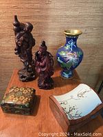 Group photo showing all 5 oriental decor pieces including vase, statuettes, and trinket boxes on a wooden table against fabric background